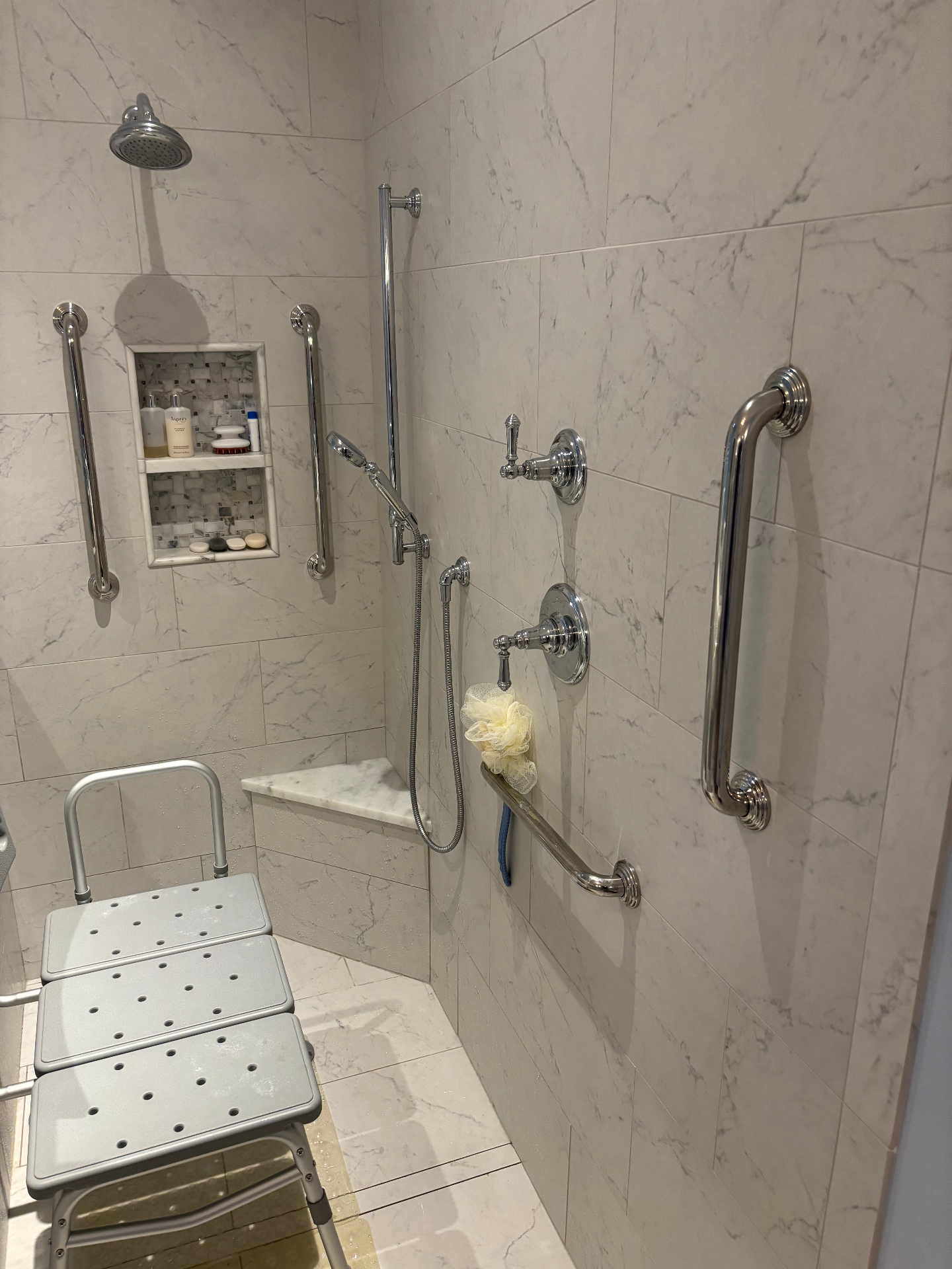 Finished marble walk-in shower with grab bars and a bench seat